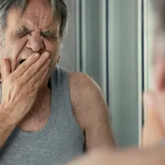 Zmęczony mężczyzna w podkoszulku z trudem powstrzymuje ziewanie, co może być oznaką stresu.