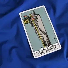 Karta Tarota "Pustelnik" (The Hermit) na niebieskim tle. Symbolizuje introspekcję, mądrość i poszukiwanie wewnętrznego światła.