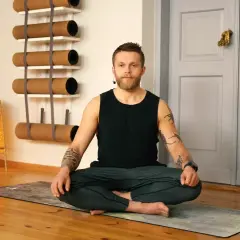 Mężczyzna w pozycji medytacyjnej na macie. Joga dla każdego, kto szuka spokoju i równowagi.