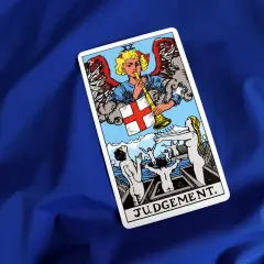 Karta Tarota Sąd Ostateczny. Anioł gra na trąbie, budząc ludzi. Znaczenie tej karty to przebudzenie i nowy początek.