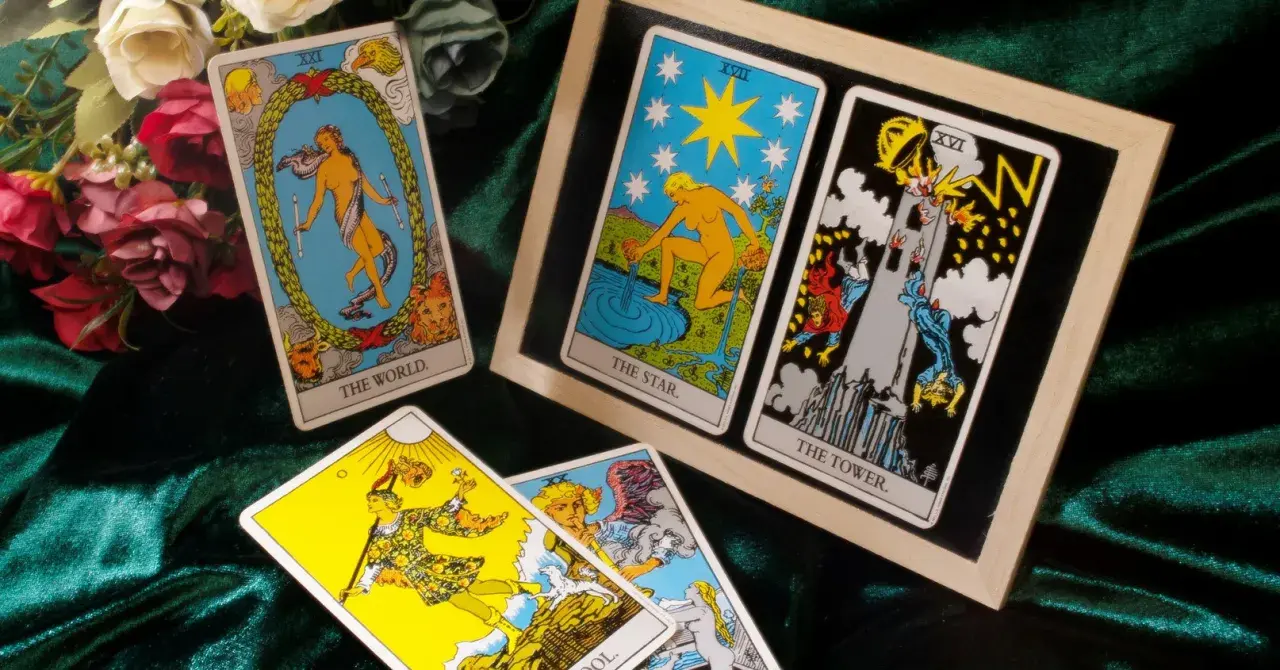 Tarot tak nie: karty Świat, Gwiazda i Wieża. Rozłożenie na aksamitnym tle, obok bukiet róż.