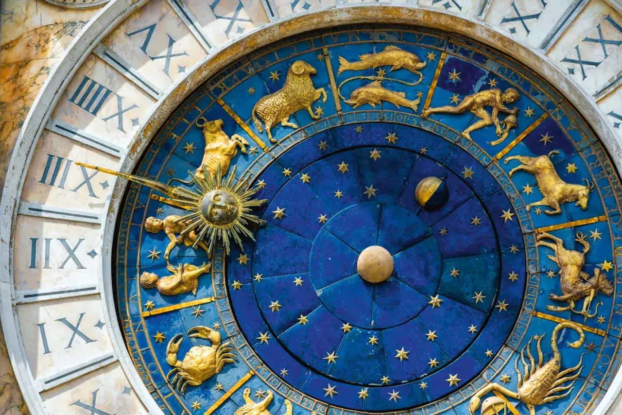 Złoty horoskop tygodniowy na niebieskiej tarczy zegara. Widoczne znaki zodiaku: Baran, Ryby, Wodnik, Koziorożec, Skorpion, Rak.